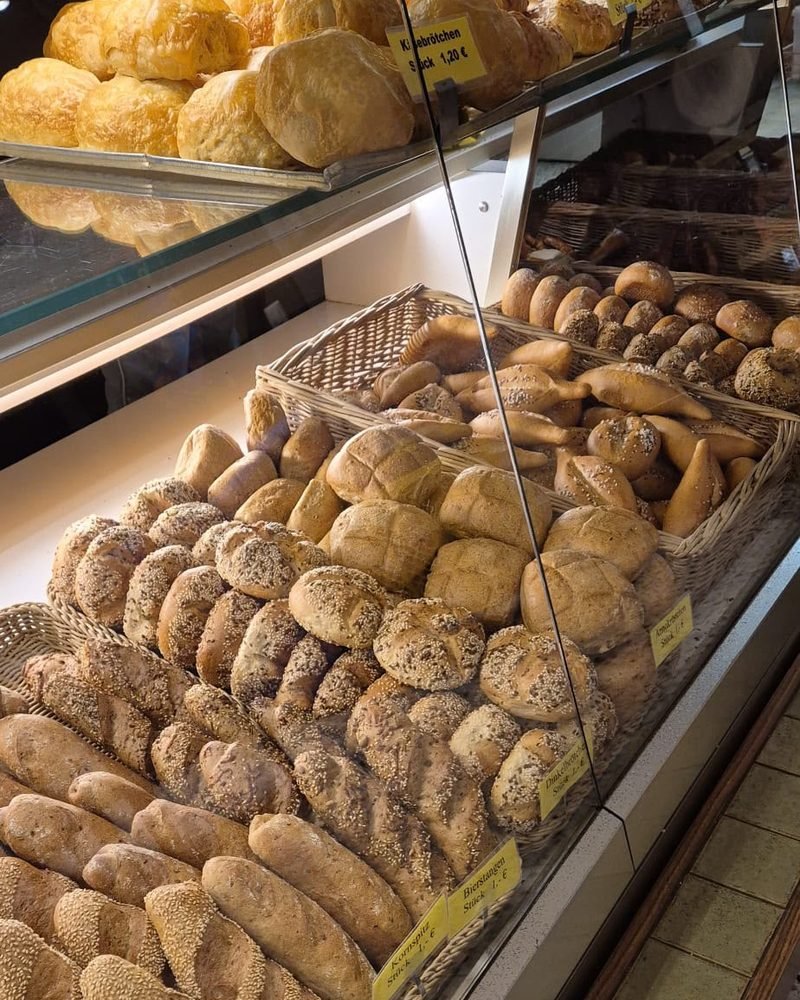 Blick in die Verkaufstheke mit Körben voller Körner-, Sesam- und Dinkelbrötchen.
